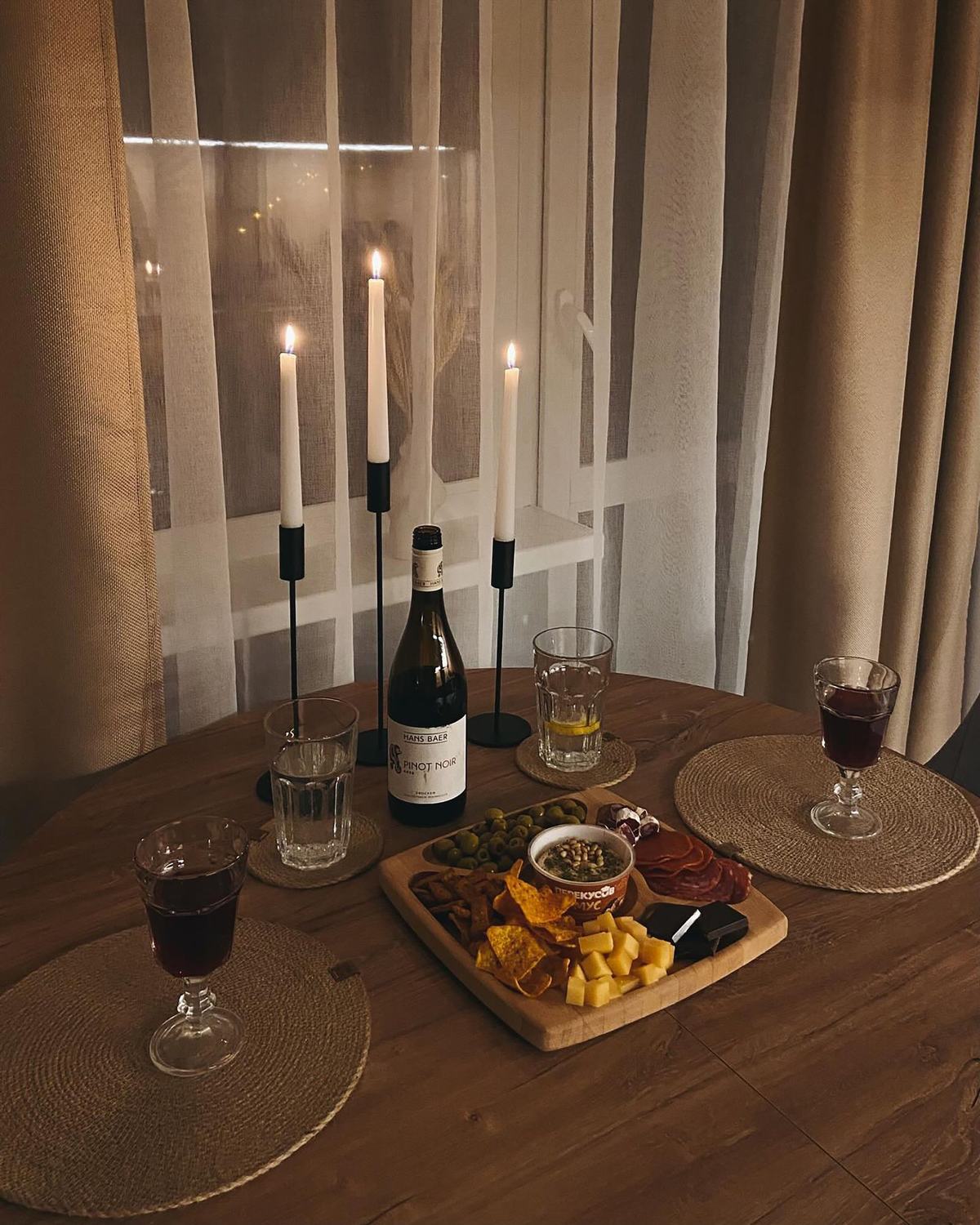 Bougies, vin et planche partagée sur une table en bois